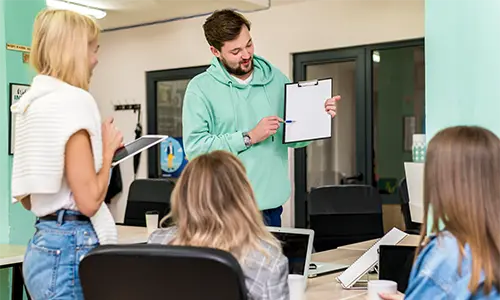 Mężczyzna prezentuje materiał przed grupą dorosłych na kursie językowym.
